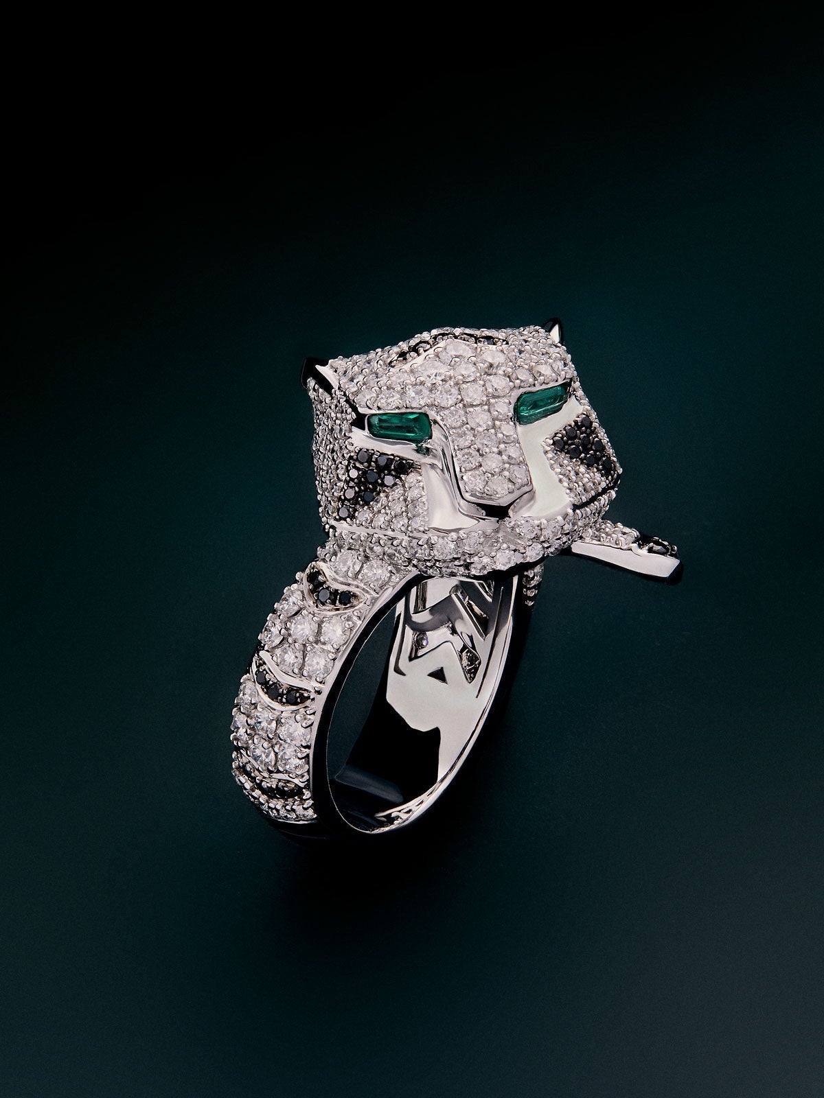 18K white gold ring with 278 brilliant-cut white diamonds with a total of 1.87 cts, 55 brilliant-cut black diamonds with a total of 0.25 cts, and 2 trapezoid-cut emeralds with a total of 0.13 tiger shaped cts