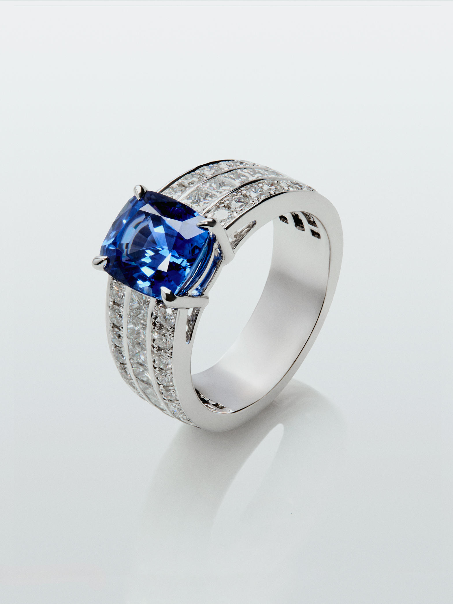 Anillo de oro blanco de 18K con zafiro azul royal en talla cushion de 3,217 cts, 50 diamantes en talla brillante con un total de 1,05 cts y 8 en talla princesa con un total de 0,48 cts
