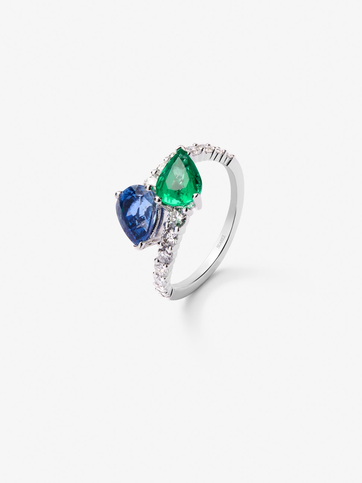 Anillo tú y yo de oro blanco de 18K con un zafiro azul intenso en talla pera de 1,49 cts, una esmeralda verde en talla pera de 1,04 cts y 14 diamantes en talla brillante con un total de 0,64 cts